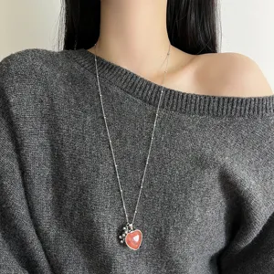 Long chain natural stone heart pendant necklace detail shot, elegant sweater chain accessory.