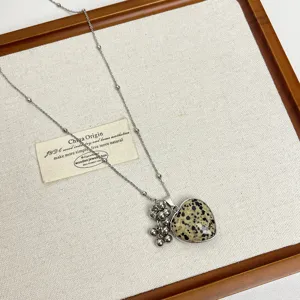 Detailed view of the long chain necklace with natural stone heart pendant and grape charm.