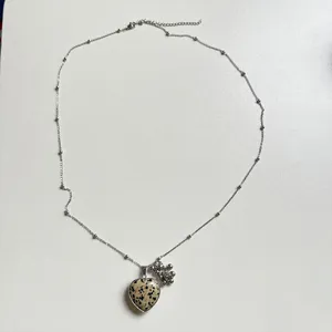 Detailed view of a long silver chain necklace featuring a dalmatian stone heart pendant.