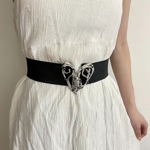 Detail view of vintage black elastic belt featuring ornate silver metal heart buckle accessory.