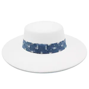 Vista detallada de un elegante sombrero blanco de ala ancha con banda de mezclilla y lentejuelas.