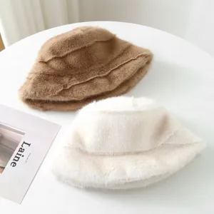Close-up detail of cozy plush faux fur bucket hats in beige and brown on a clean table.