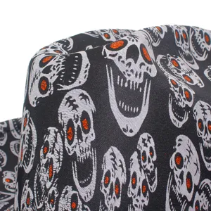 Halloween skull cowboy hat detail shot featuring black fabric with white skulls and orange glitter.