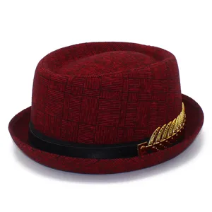 Detail shot of the red patterned fedora hat showing exquisite golden leaf accessory and band.