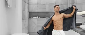 Detailed scene of soft thickened dark grey coral fleece bath towel in modern bathroom.