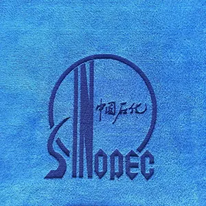 Close-up detail of blue microfiber towel fabric with clear embroidered logo texture.