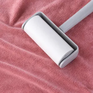 Rullo levapelucchi grigio in plastica su asciugamano rosa per la pulizia quotidiana
