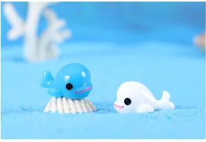 Gros plan de mignonnes figurines de dauphins en résine bleue et blanche pour micro-paysage.