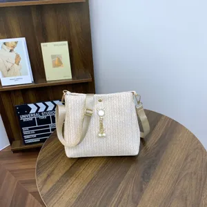 Woven straw shoulder bag for women, stylish casual crossbody bag with pearl charm and strap.
