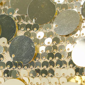 Gold sequin fabric detail macro shot, sparkling paillettes texture for evening bags and dresses.