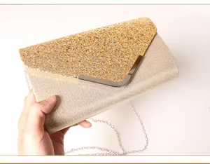 Gold glitter envelope clutch purse detail, elegant party evening bag with metal chain strap.