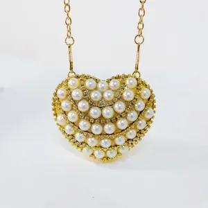 Closeup detail of the glamorous heart-shaped pearl rhinestone evening bag with gold chain strap.