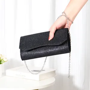 Black glitter evening clutch bag detail showing sparkling texture and silver metal chain.