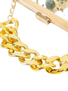 Detail view of a luxury gold chunky chain and metallic frame on a sparkling evening clutch bag.