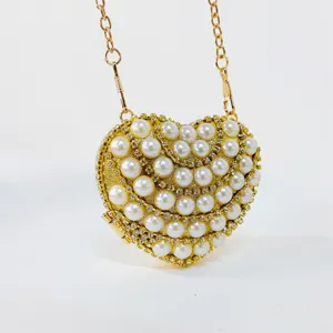 Gold heart evening bag detail featuring sparkling pearls and rhinestones with chain.