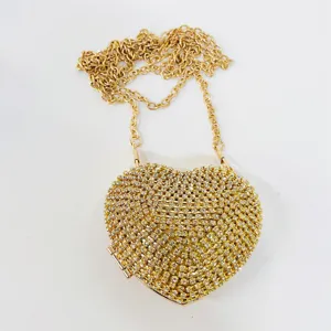 Detailed shot of sparkling rhinestone heart evening bag with gold chain strap and clasp.