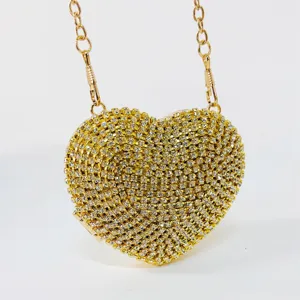 Heart-shaped crystal clutch bag detail featuring sparkling rhinestones and gold chain handle.