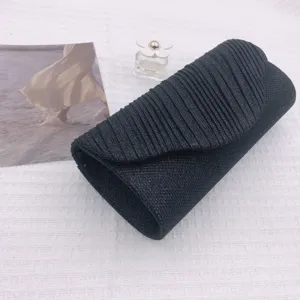 Black pleated clutch evening bag detail, elegant textured fabric design for party wear.