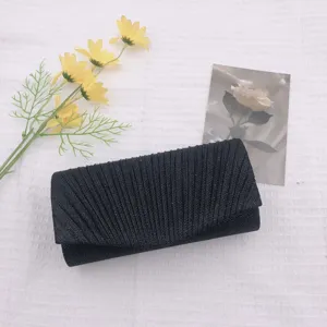 Black pleated evening clutch bag detail view, shimmering fabric with delicate fold design.