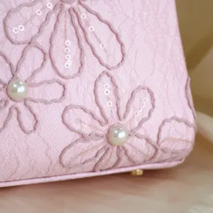 Close-up detail of pink embroidered handbag with delicate floral sequins and pearl accents.