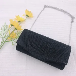 Detail shot of black pleated evening clutch bag with silver chain strap for elegant look.