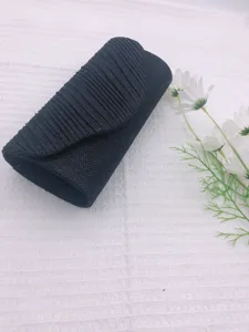 Black pleated evening clutch bag detail view, elegant textured design for formal events.