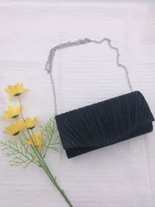 Detailed view of the black pleated evening clutch bag with silver chain strap and flowers.