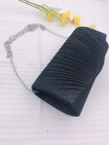 Close-up detail of the black pleated evening clutch showcasing glitter fabric and fine metallic chain.