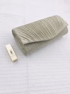 Detail view of pleated metallic evening clutch bag with flap closure and refined texture.