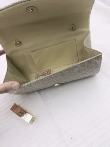 Detail view of the shimmering gold evening clutch bag interior, featuring a pocket and chain.