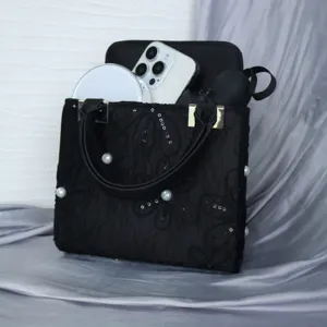 Detailed view of black Chinese style embroidered evening handbag with pearl and sequin decor.