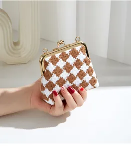 Κοντινή λήψη λεπτομέρειας τσάντας clutch με μοτίβο pied-de-poule και μεταλλικό κούμπωμα.