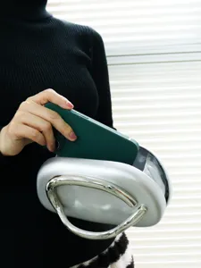 Detailed view of silver metallic evening bag with unique metal handle showing interior.