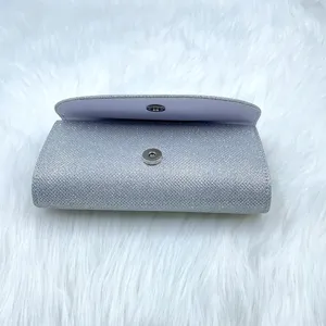 Silver glitter evening clutch bag detail, elegant flap design with secure magnetic snap closure.