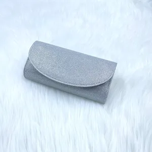 Detail shot of a silver glitter clutch bag featuring a sleek flap design for evening wear.