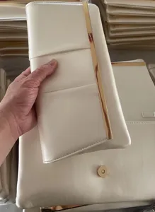 Elegant cream white evening clutch bag with vertical gold metal bar detail, premium fashion accessory