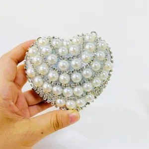 Close-up detail of a sparkling heart-shaped evening clutch with pearls and rhinestones.
