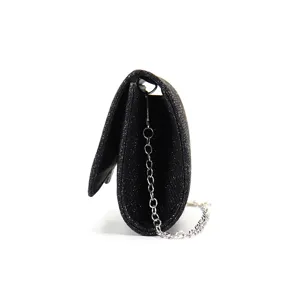 Detailed side view of a black glitter evening bag with a silver chain strap showing texture.