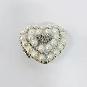 Detailed view of the heart-shaped evening clutch bag adorned with pearls and rhinestones.
