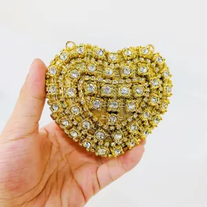 Detail view of a glamorous heart-shaped evening clutch covered in sparkling gold rhinestones.