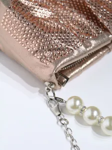 Close-up detail of shimmering rhinestone evening clutch bag with pearl chain strap.