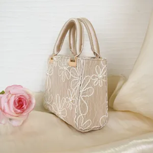 Detailed shot of the elegant champagne satin evening bag with delicate floral embroidery.