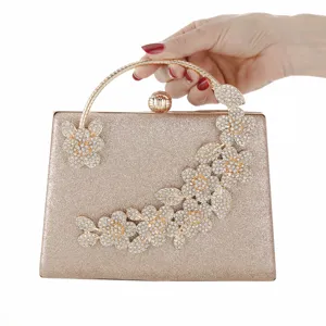 Elegant champagne gold glitter evening clutch bag with sparkling rhinestone flower and metal ring handle.