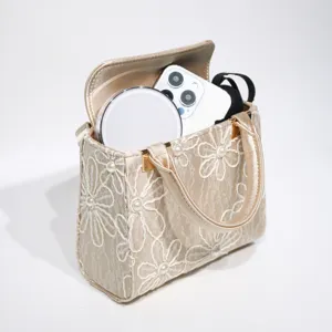 Detailed view of champagne floral lace handbag featuring exquisite pearls and inner items.