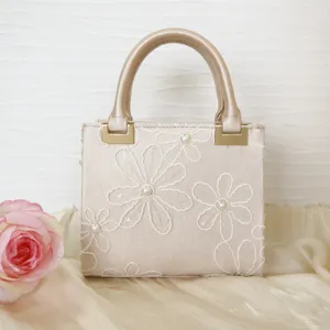 Close-up detail of beige beaded floral embroidered handbag, elegant evening purse design.