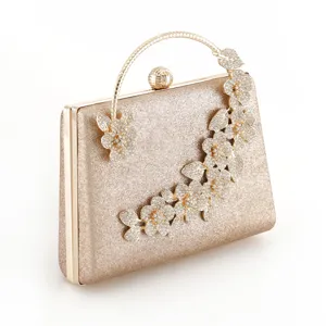 Elegant gold glitter evening clutch bag with sparkling rhinestone flower and metal handle.