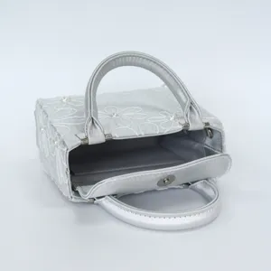 Detailed view of the elegant silver embroidered evening bag with floral patterns and pearls.
