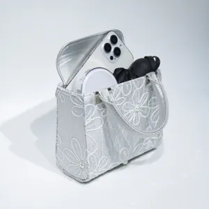 Silver embroidered evening handbag detail showcasing capacity and delicate floral patterns.