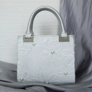 Close-up detail of silver embroidered evening handbag with pearl and sequin embellishments.