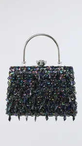Close-up detail of the glittering sequin evening bag featuring a shiny metal top handle.